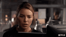 a woman is looking at a computer screen with a netflix logo behind her