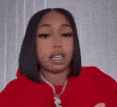 a woman in a red hoodie and necklace is looking at the camera .