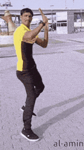 a man in a yellow shirt and black pants is dancing on a brick sidewalk with the name al-amin on the bottom
