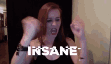 a woman is screaming with her fist in the air and the word insane is on the screen behind her
