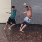 two men are playing with a ball in a room and one of them is throwing the ball .