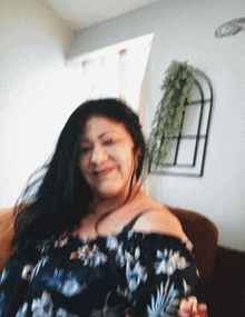 a woman in a black floral off the shoulder top smiles