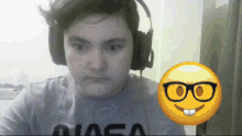 a man wearing headphones and a nasa shirt looks at the camera