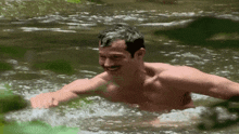 a shirtless man is swimming in a river