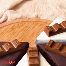 a wooden cutting board with a few pieces of chocolate and the words yum up on the bottom right