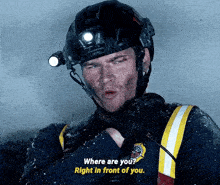 a man wearing a helmet with a light on his head says where are you right in front of you