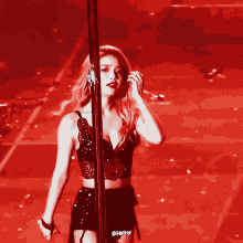 a woman in a black dress is standing on a pole in front of a red background that says phmio