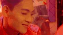 a close up of a man 's face with his eyes closed and a red background .