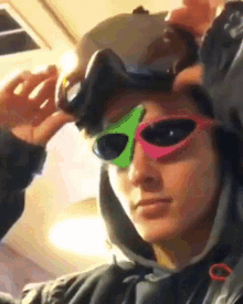 a man wearing a helmet and sunglasses with a green triangle on the lenses