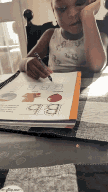 a little girl is writing in a notebook with the letter bb on it