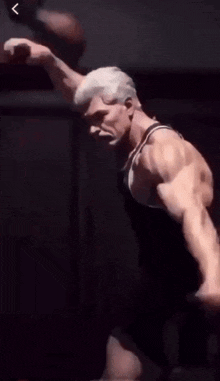 a man in a black tank top is flexing his muscles