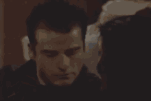 a close up of a man 's face with a woman 's hand on his ear .