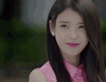 a woman wearing a pink shirt and earrings is smiling