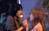 two women are holding hands and looking at each other in a dark room .