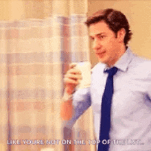 a man in a blue shirt and tie is holding a cup of coffee in his hand .