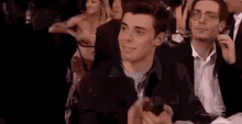 a group of young men are sitting in a theatre applauding and smiling .