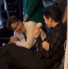 two men are sitting next to each other and one is holding something