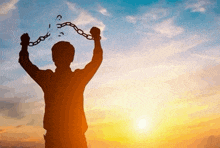 a silhouette of a man holding chains in his hands .