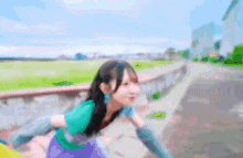a blurry picture of a girl in a green shirt and purple skirt
