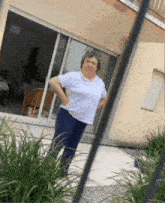 a woman in a white shirt and blue pants is standing in front of a sliding glass door