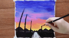 a person is painting a sunset over a road with a brush