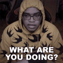 a man wearing a yellow hoodie with black birds on it says what are you doing