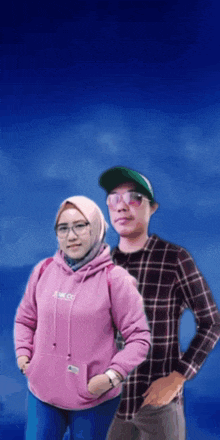 a man and a woman are posing for a picture and the woman is wearing a pink hoodie that says raw co.