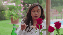 a woman is sitting at a table with roses and a bottle of water with the real housewives logo on the bottom