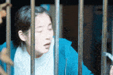 a woman behind bars with her eyes closed and a surprised look on her face