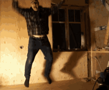 a man in a plaid shirt is jumping in the air in front of a window