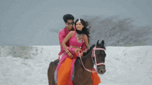 a man and woman are riding a horse in the snow .