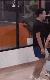 a man in a black shirt and blue shorts is dancing in a room