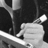 a black and white photo of a person holding a pair of scissors in their hand .
