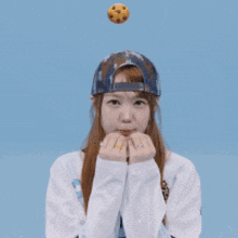 a girl wearing a baseball cap is holding a cookie in her hands