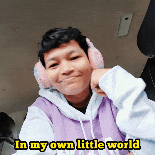 a boy wearing ear muffs and a purple hoodie with the words in my own little world above him