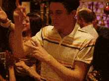 a man in a striped shirt is dancing in a crowded room