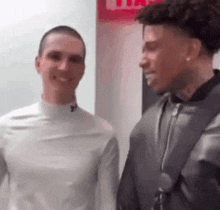 two men are standing next to each other and talking to each other .