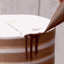 a person is piping chocolate on a cake with a pastry bag