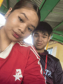 a boy and a girl are posing for a picture and the girl is wearing a red shirt with a star on it