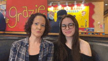 a woman and a girl are posing for a picture in front of a sign that says grazie