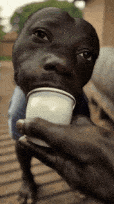 a close up of a person holding a cup in front of a child 's face