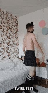 a shirtless man wearing a kilt and knee high socks is standing in a room .