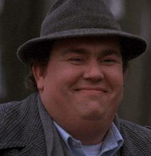 a man wearing a hat and a suit is smiling for the camera