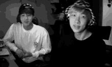 a black and white photo of two young men wearing hats and sweaters