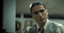 a man with long hair is wearing a vest and a tie