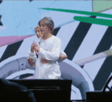 a man in a white shirt holds a microphone while another man hugs him
