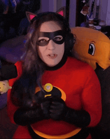 a woman wearing a cat ear mask and a red superhero costume