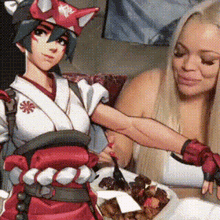 two women are sitting at a table with plates of food and a cartoon character .
