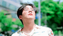a man wearing glasses and a floral shirt is looking up at the sky