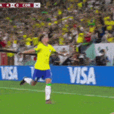 a soccer player celebrates a goal in front of a visa ad